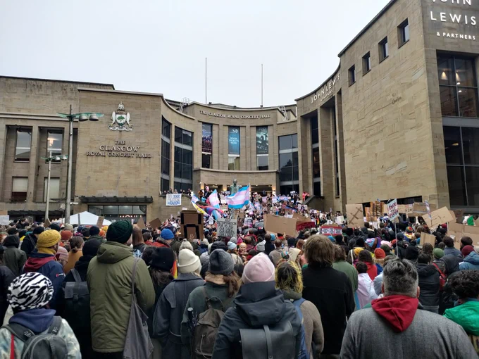 A large group of people gathered on Buchanan gallery steps in Glasgow to protest the blocking of the GRR Bill, with trans flags flying alongside many homemade signs and banners