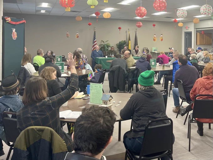 A photo of the greenfield coffee klatch featuring a woman raising her hand to ask a question