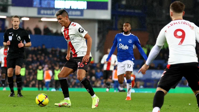 Charly Alcaraz dribbles forward in space with the ball at his feet, with an Everton player seen in the background.