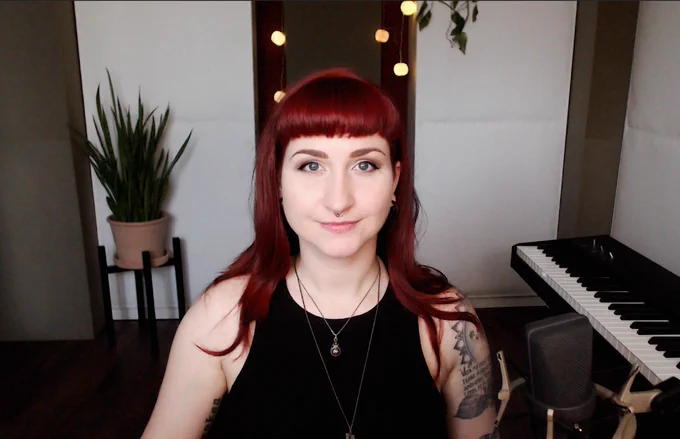 Photo of me (a smiling woman with red hair) with a cozy looking studio in the background