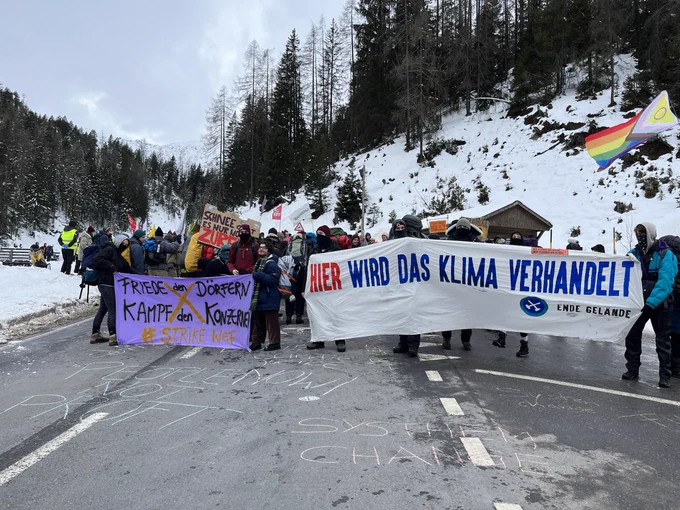 Die Strike WEF Demo auf einer Bergstraße mit Bannern in Solidarität mit Lützerath und mit „Hier wird Klimagerechtigkeit verhandelt“