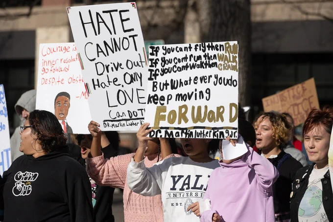 People hold signs while marching in the M L K Day March, signs are quotes from Martin Luther King, Jr. "Hate cannot drive out hate. Only love can do that." "If you can't fly then run. If you can't run then walk. If you can't walk then crawl. But whatever you do, keep moving forward." 