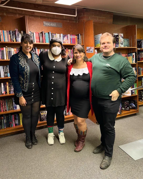 Alycia, Nisha, Adriana and Matthew pose for a photo in front of a bookshelf.