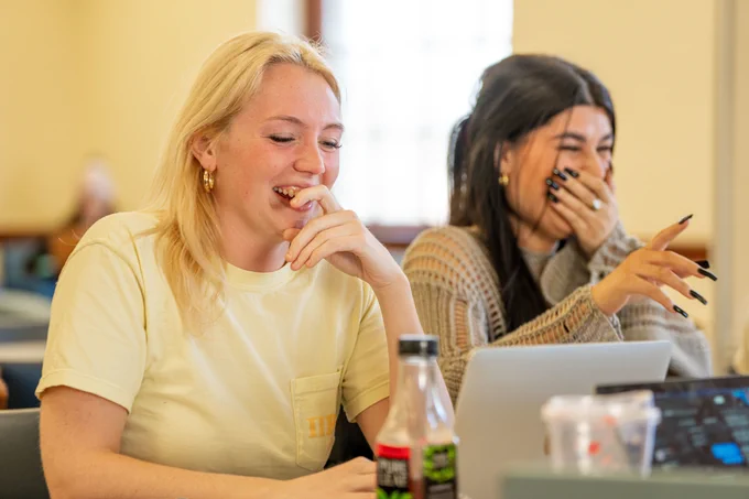 Two students laugh while working in Fogler Library.