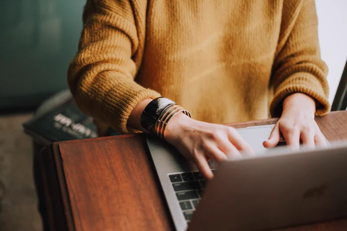 Hands type on a laptop keyboard.