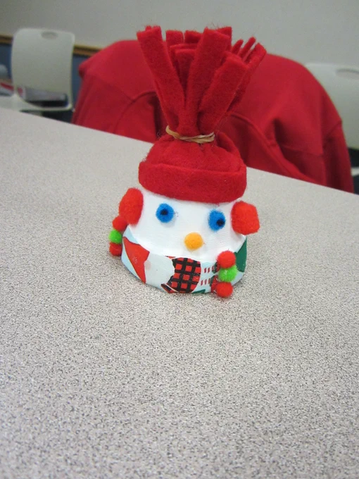 A snowman in a red hat with a santa scarf