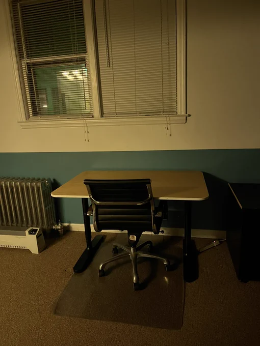 Wooden desk with an office chair in a dimly lit coworking space