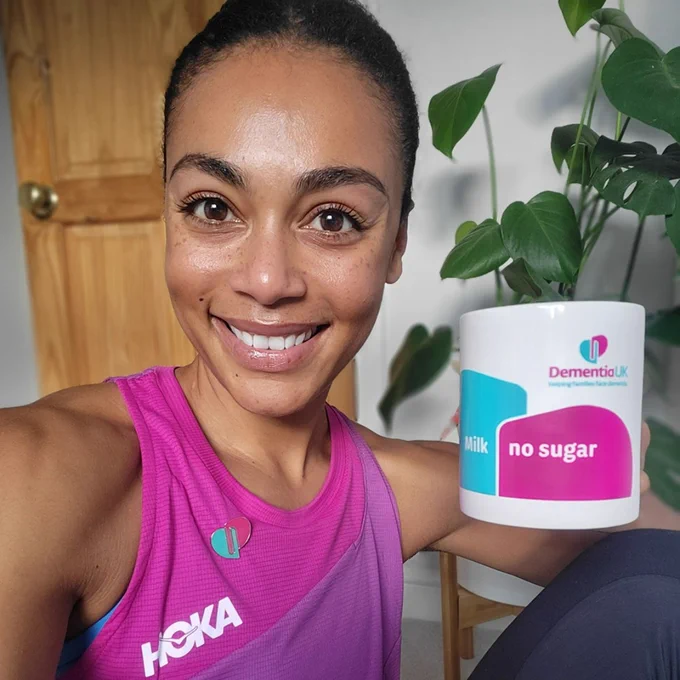 Adelle Tracey smiles as she holds up a Dementia UK branded mug.