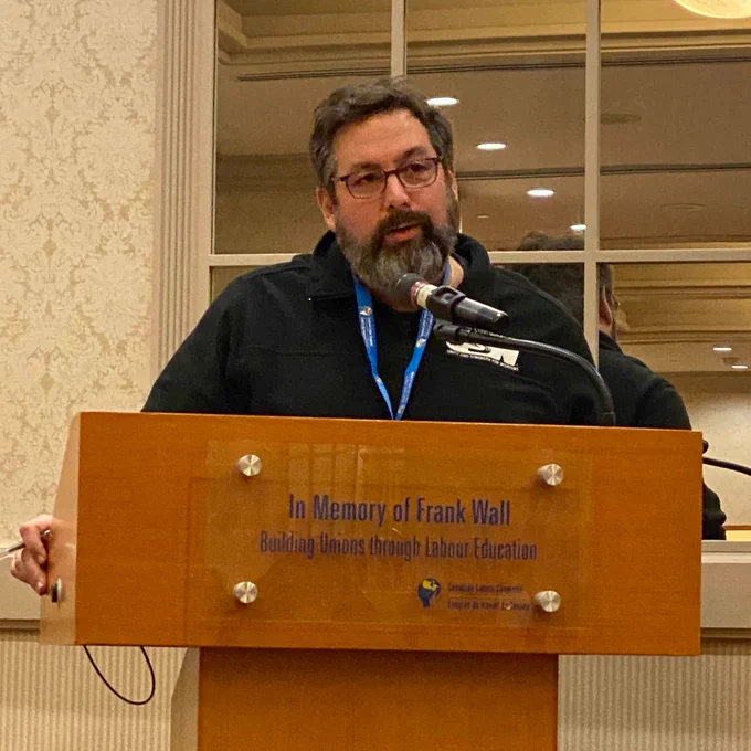 Scott looks thoughtful as he speaks at the lectern