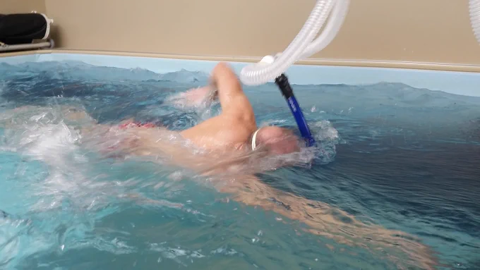 Swimmer in endless pool with hoses connected to a snorkel