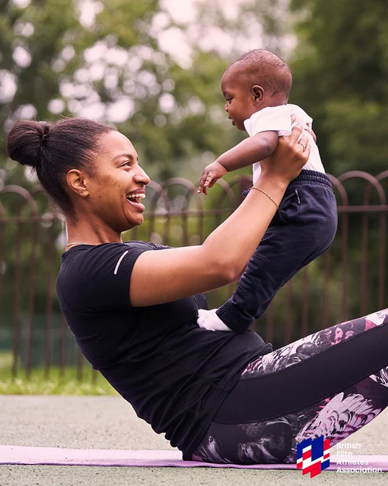 A woman on a yoga mat lifts a baby onto her torso.