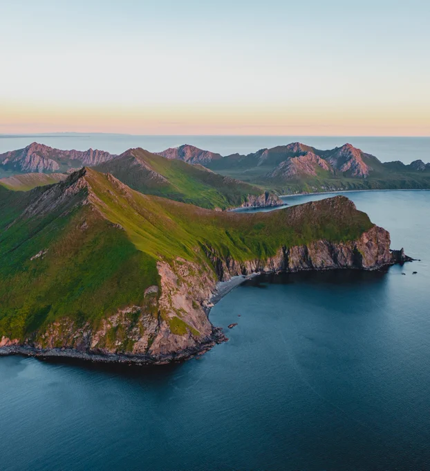 a shot of a cliffside and mountains at sunset near Kodiak Island. Photo taken by alaska photographer, Ellen Carty