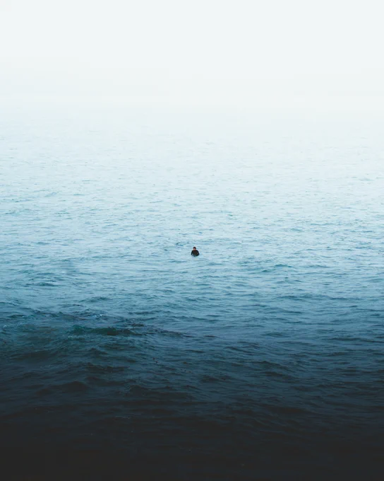 a lone surfer waiting to catch a wave on a foggy day near Kodiak Island. Photo taken by alaska photographer, Ellen Carty