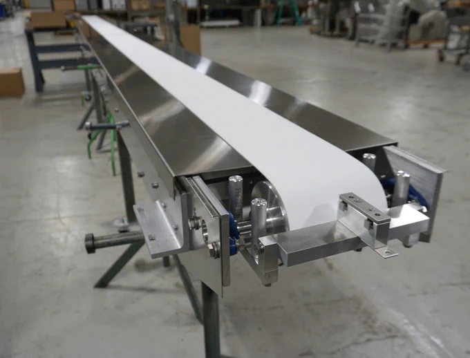 Long flow wrapper with white vinyl conveyor belt. This particular Horizontal Flow Wrapper has been outfitted with a continuous vinyl conveyor belt, allowing for longer items to be fed into the seal assembly.