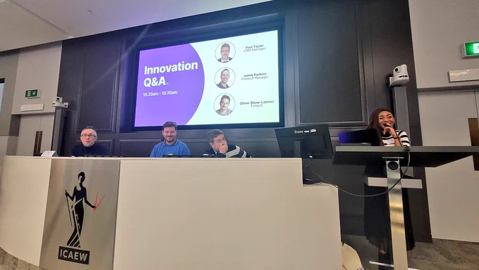 A panel of people sit in a row. Jordyn from JustGiving stands to the right.