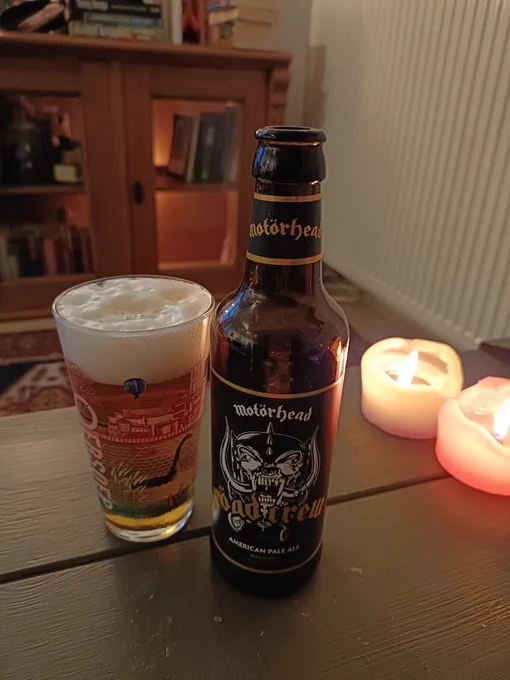 Glass of beer next to a beer bottle with the Motörhead logo on it