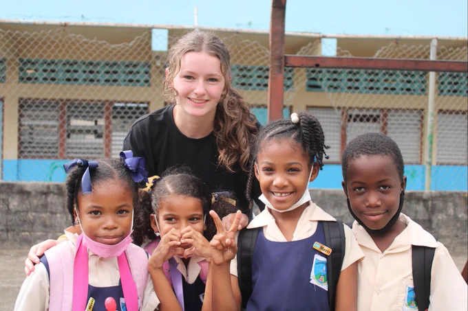 A photo of a DN Colleges Group student posing with the primary school students.