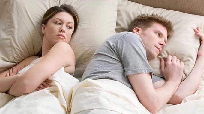 man looking away from woman while laying in bed