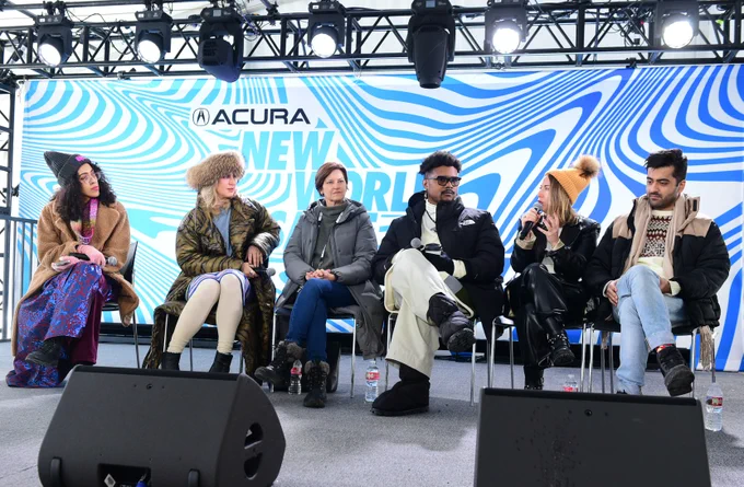 Five panelists and a moderator sit on the Outfest Outpost stage.