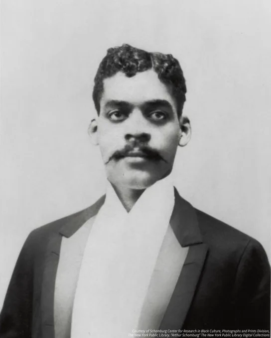  Black and white photo of Arthur Schomburg in suit with styled hair and a mustache. 