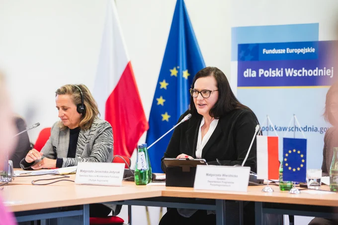 Dwie osoby siedzą przy stole. Druga z lewej siedzi wiceminister Małgorzata Jarosińska-Jedynak i mówi do mikrofonu.
