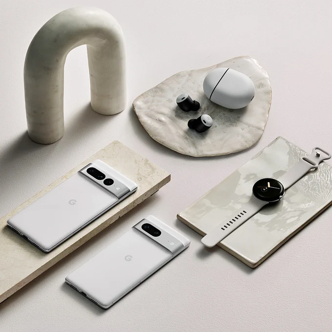 The Google Pixel 7 and Pixel 7 Pro in Snow, Pixel Buds Pro in Fog and Pixel Watch in Polished Silver case / Chalk Active band on a white background.