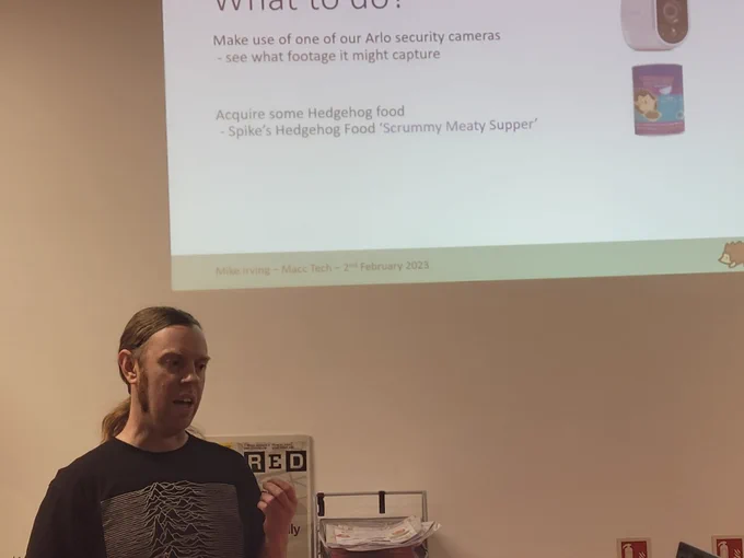 Mike Irving presenting his IoT and Hedgehogs talk. Slide shows the Arlo security camera and the Hedgehog food he used