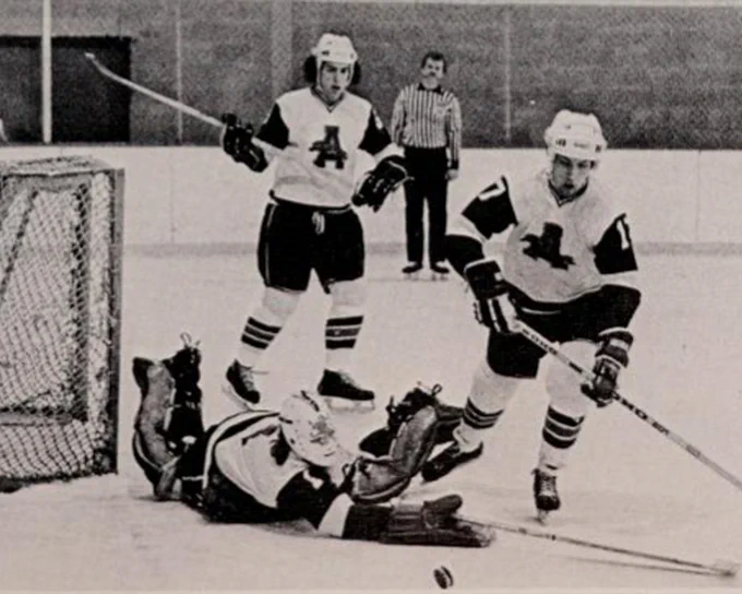 Photo of the Assumption University Greyhounds men's ice hockey team blocking a shot away from the net during the 1976-77 season.