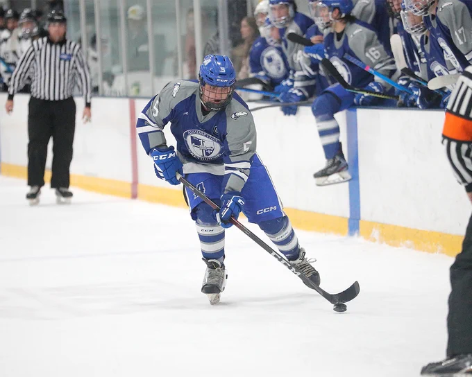Assumption University's Michael Zampanti (Graduate Student, F #5) controls the puck in front of the Greyhounds bench.