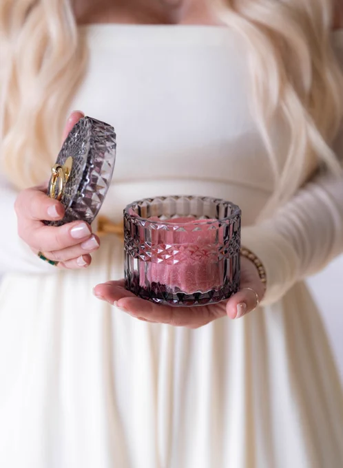 A women holds a ping candle in her hand. You see a close-up of the woman holding the candle with the top off.
