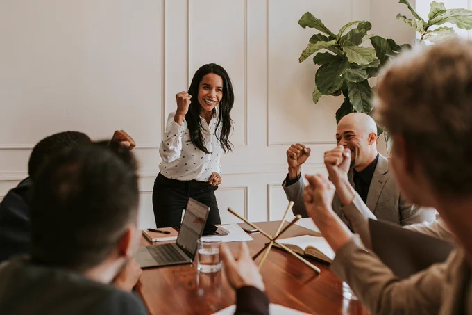 Woman leads strategy team in a boardroom, showing excitement for success of positive results.
