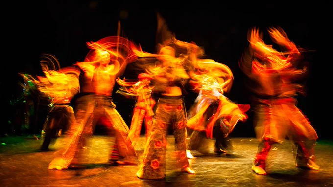 Dancers in bright costumes on a dark stage.