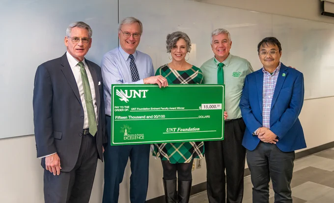 Department chair Simon Andrew, UNT Foundation President and CEO Mike Mlinac, and UNT faculty leaders surprise Bob Bland with his Eminent Faculty Award giant check during class