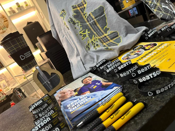 A showcase table featuring merchandise including pens, leaflets and wristbands from Beatson Charity