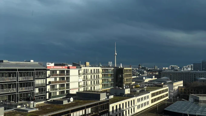 Der Blick aus dem Fenster bei blauem Himmel, man sieht einige Hausfassaden und den Fernsehturm.
