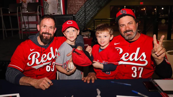 Sam LeCure and Corky Miller pose with a pair of young fans.