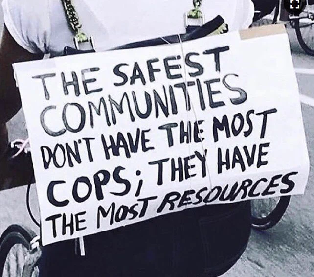 Protest sign that reads “ the safest communities don’t have the most cops; they have the most resources”