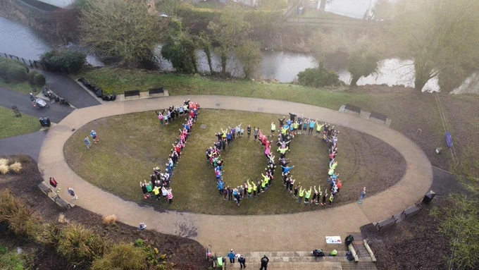 An image taken high up in the air from a drone of people in the shape of the number one hundred, made up with a combination of runners and volunteers to celebrate our 100th milestone.