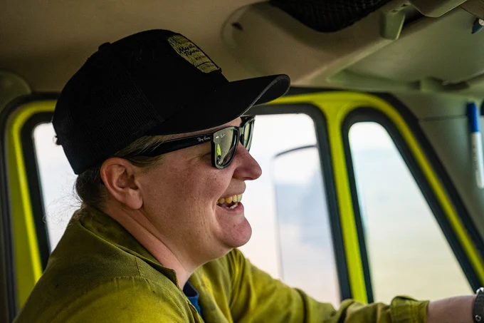 A side view of a wildland firefighter smiling while driving an engine. Photo by Colby Neal, BLM.