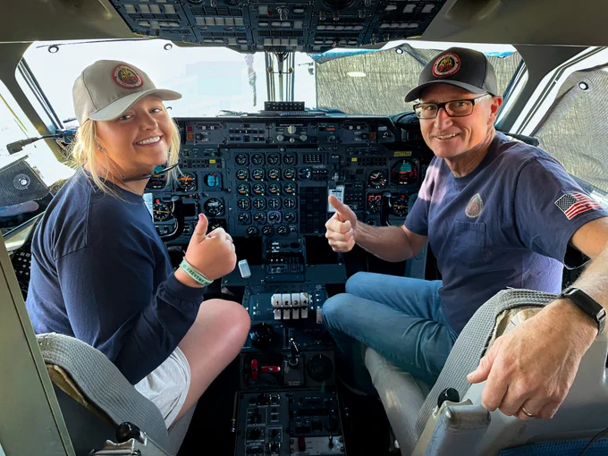 Two people sit in the front of an airtanker at the Twin Falls Airbase in Idaho. They are smiling, turning in their seats to give a thumbs up to the camera. Photo by Abby Brinkley, BLM.