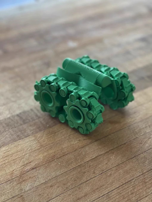 3D printed tank/bot sitting on wooden butcher block counter.