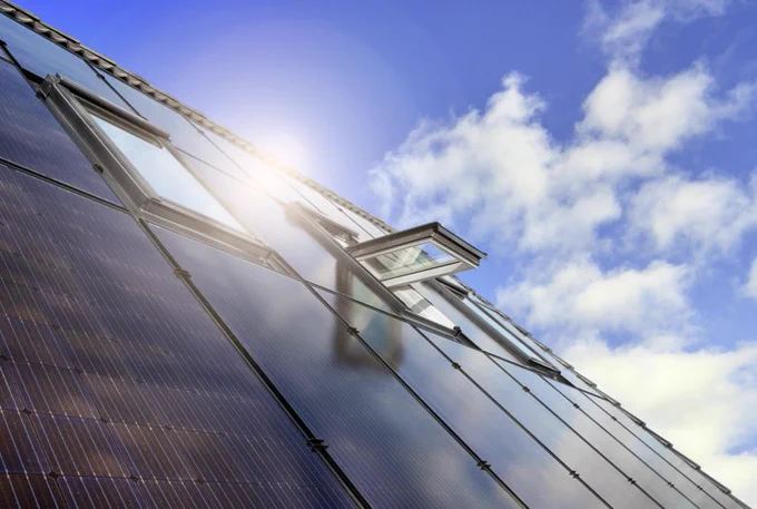 A roof covered with Velux windows and solar panels against a beautiful blue sky.