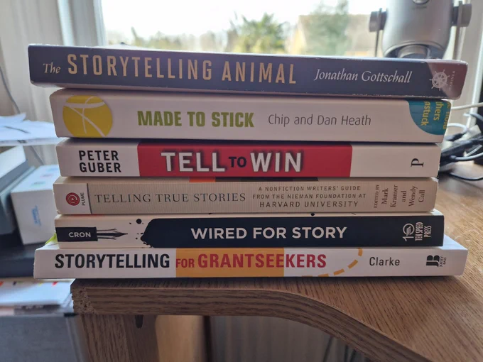 A stack of six books about storytelling. It includes The Storytelling Animal, Made to Stick, Tell to Win, Telling True Stories, Wired for Story and Storytelling for Grantseekers