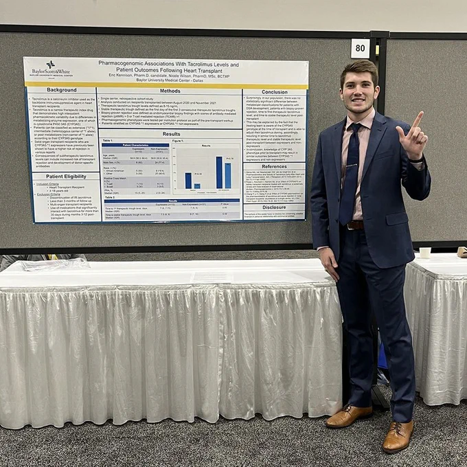 Male TTUHSC pharmacy student stands in front of his research poster at a conference.