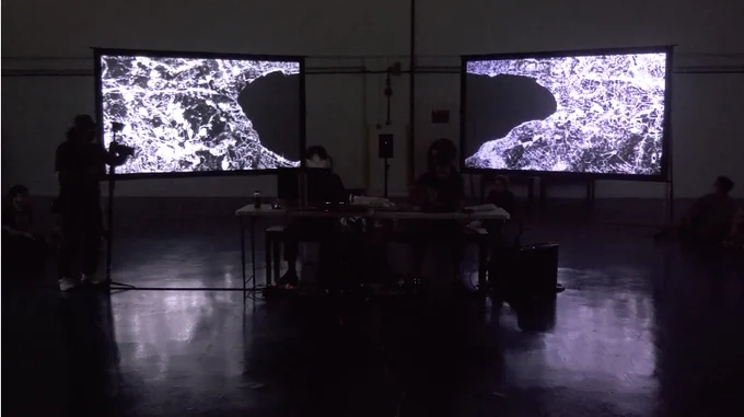 a screenshot of the performance consisting of 2 large panels with mirrored images of a black and white aerial view of the area surrounding the dead sea