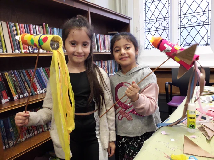 Two girls holding the rainbow Rockets they made