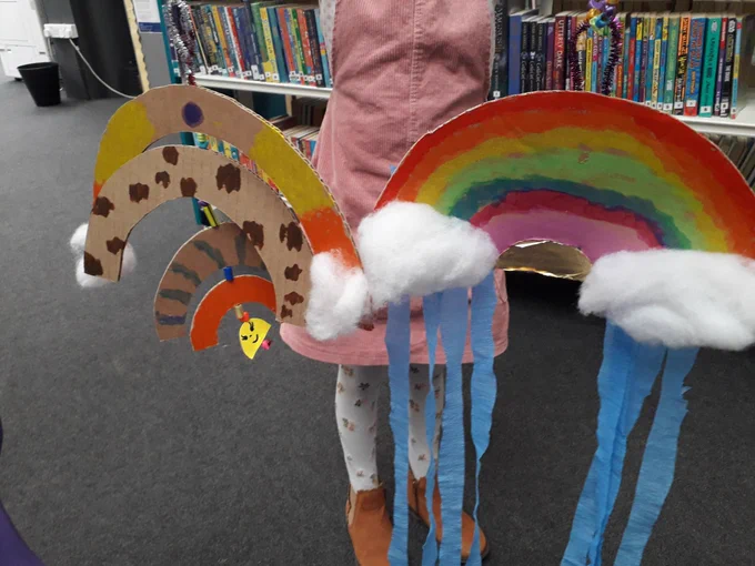 Child holding the rainbow mobiles she made