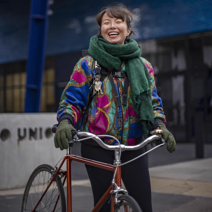 A smiling woman standing holding her bike