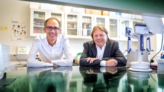 Two UNC Charlotte researchers smile for the camera in a lab.