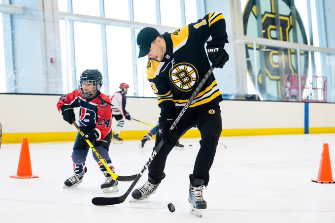 Charlie Coyle stickhandles during a drill with a Brookline youth hockey player.